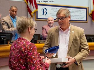 City of Bryan photo of mayor Andrew Nelson presenting Donna Adcock with a state flag that flew over the state capitol during the February 8, 2022 city council meeting.