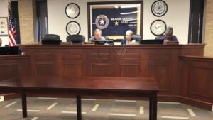 From the October 20, 2022 Brazos County commission meeting (L-R) the empty chairs of commissioners Steve Aldrich and Russ Ford, followed by county judge Duane Peters and commissioners Nancy Berry and Irma Cauley.