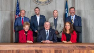 Photo from the city of College Station (seated L-R) councilwoman Linda Harvell, mayor John Nichols, and councilwoman Elizabeth Cunha (standing L-R) councilmen Mark Smith, William Wright, Dennis Maloney, and Bob Yancy.