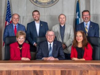 Photo from the city of College Station (seated L-R) councilwoman Linda Harvell, mayor John Nichols, and councilwoman Elizabeth Cunha (standing L-R) councilmen Mark Smith, William Wright, Dennis Maloney, and Bob Yancy.