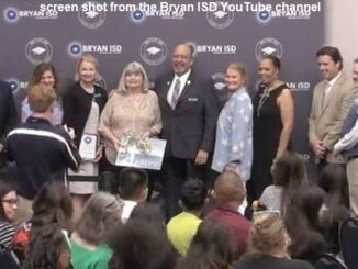 Screen shot from Bryan ISD's YouTube channel with Janice Williamson (fourth from the left) surrounded by school board members and the superintendent.