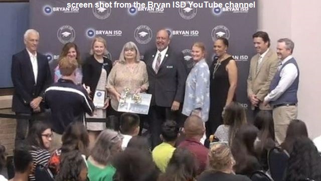 Screen shot from Bryan ISD's YouTube channel with Janice Williamson (fourth from the left) surrounded by school board members and the superintendent.