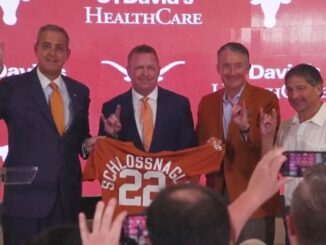 (L-R) University of Texas athletic director Chris Del Conte, Jim Schlossnagle, U-T president Jay Hartzell, and the chairman of the U-T system board of regents Kevin Eltife. Screen shot from https://texassports.com/showcase/embed.aspx?Live=747