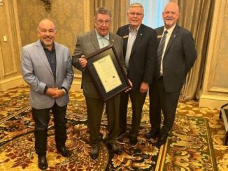 Louis Newman III holding a framed copy of a mayoral proclamation he received at the Leadership Brazos Alumni Association luncheon on July 25, 2024. Standing (L-R) are Bryan mayor Bobby Gutierrez, Louis Newman III, College Station mayor John Nichols, and the president of the Bryan/College Station chamber of commerce Glen Brewer.