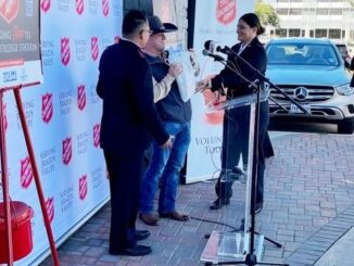 (L & R) B/CS Salvation Army captains Luis and Marianne Villanueva present (C) Charlie Borowczak a bag containing the names of 856 children who will receive gifts through the Angel Tree donations collected in Borowczyk's annual "Charlie's Angels" drive.