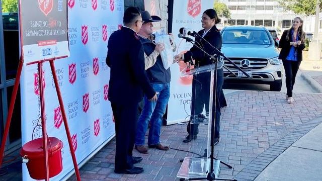 (L & R) B/CS Salvation Army captains Luis and Marianne Villanueva present (C) Charlie Borowczak a bag containing the names of 856 children who will receive gifts through the Angel Tree donations collected in Borowczyk's annual "Charlie's Angels" drive.