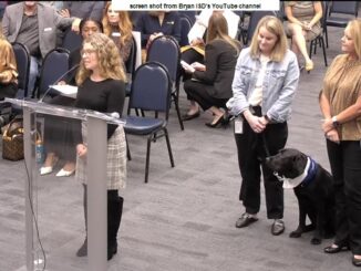 Screen shot from Bryan ISD's YouTube channel showing (L-R) Sarah Braden of the Bryan ISD education foundation, Kemp-Carver elementary school principal Alison Boggan, comfort dog June, and Kemp-Carver principal Cara Peters.